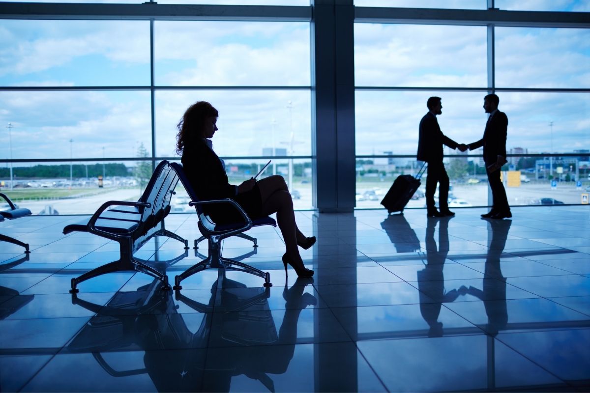 funcionários em aeroporto esperando para começar viagem corporativa